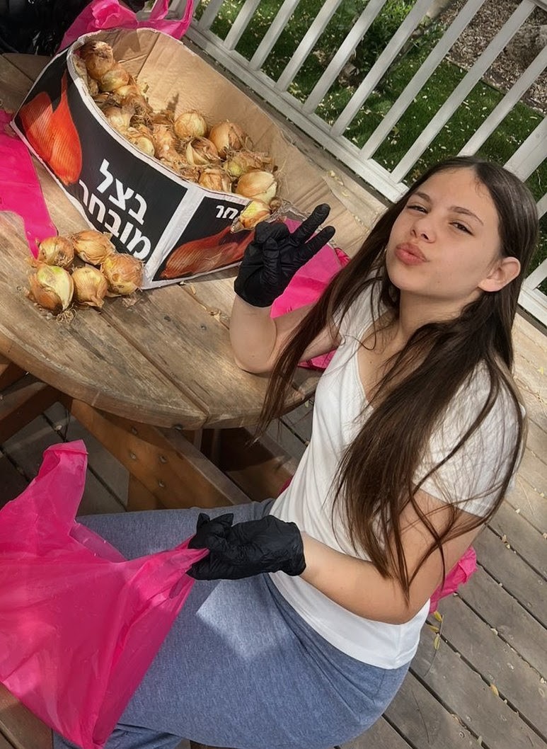 Student wearing gloves beside onions and produce bags