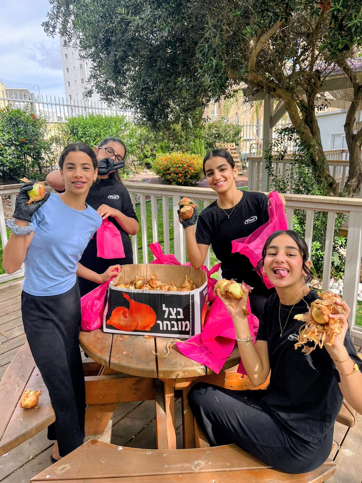 Students with gloves sorting onions around a courtyard table