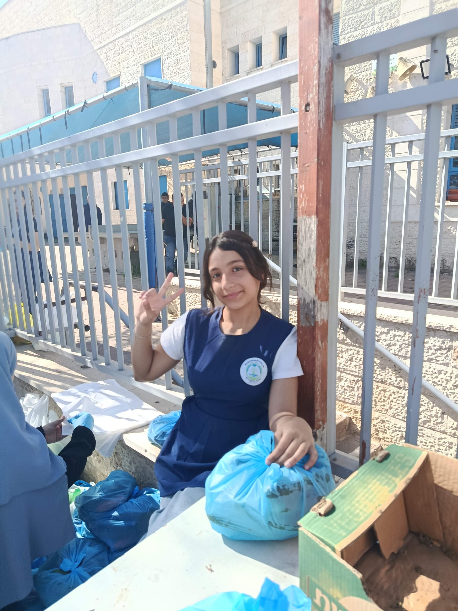 Student wearing gloves with packed produce bags at a school table