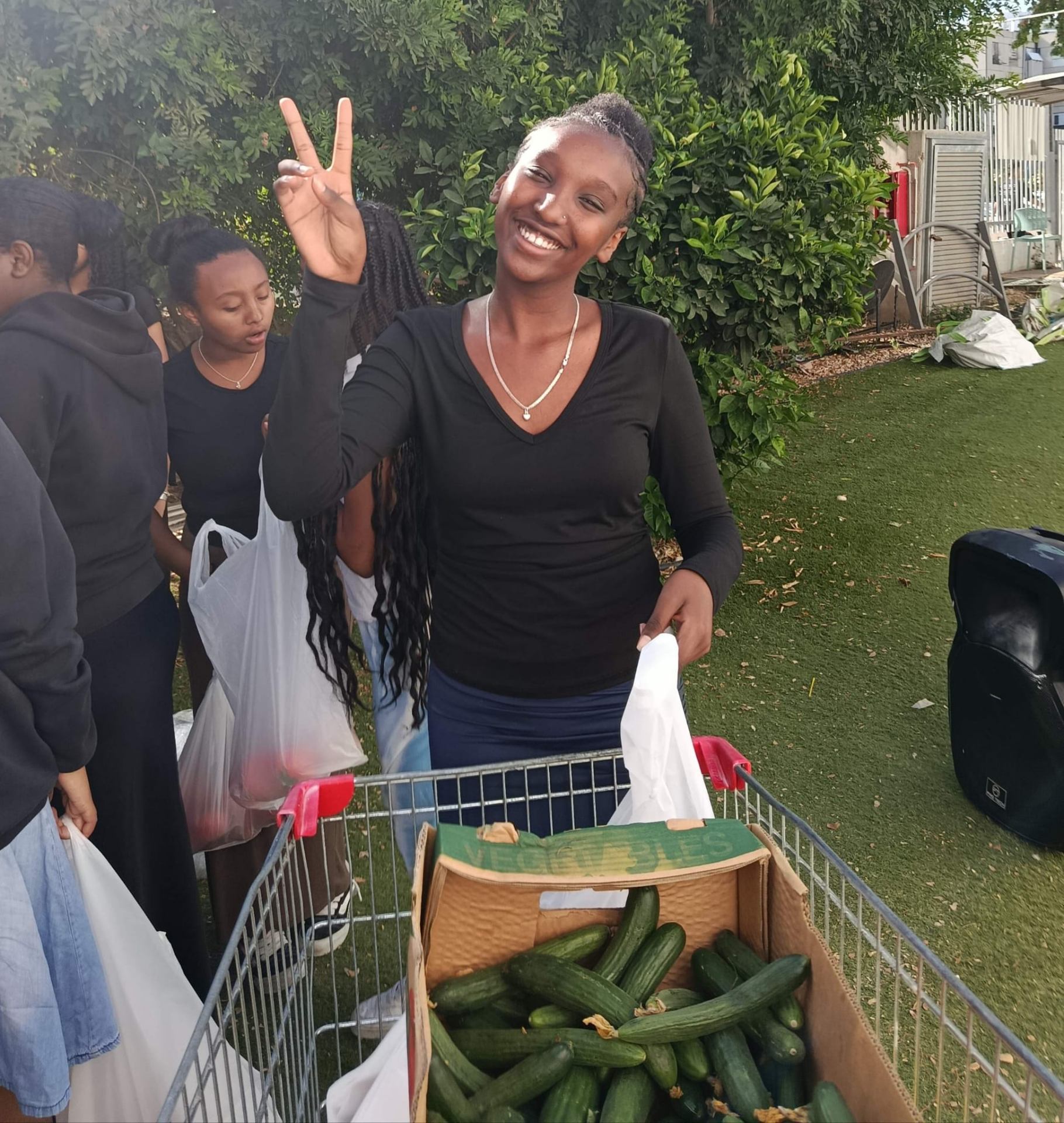 Participant beside a crate of cucumbers and bags of produce